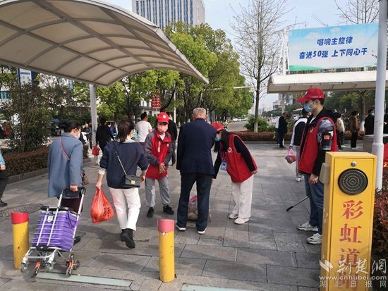 志愿服務(wù)隊在人民醫(yī)院路口開展文明交通體驗活動，并幫助老人提重物.jpg.jpg