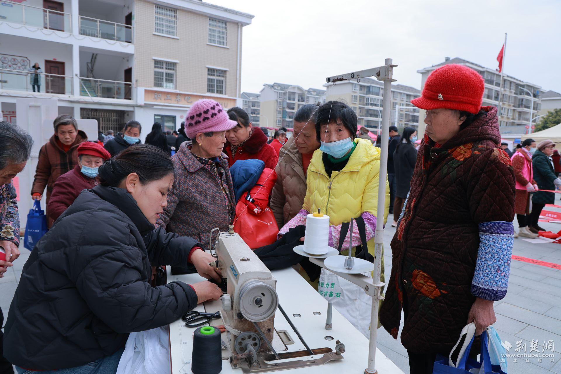 衣物縫補(bǔ)攤前，志愿者飛針走線為居民修補(bǔ)破損衣物.jpg.jpg